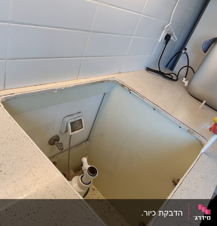 אדם עם כפפות צהובות מחזיק אקדח סיליקון ליד כיור פתוח